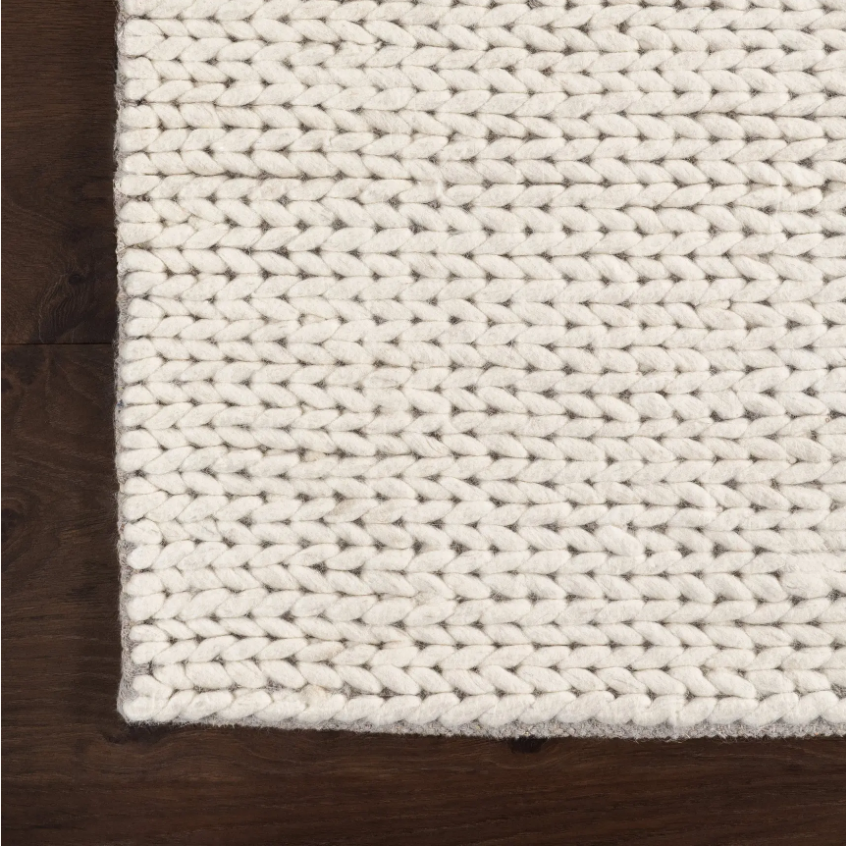 Close-up of a textured white rug on a wooden floor