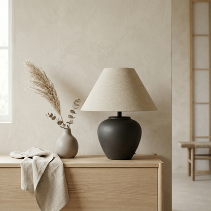 Minimalist ceramic table lamp with rounded black base and warm linen shade in a Japandi interior