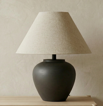 Minimalist black ceramic table lamp with a rounded ceramic base and a warm linen shade for Japandi and Scandinavian interiors