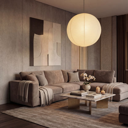 Round rice paper pendant light illuminating a modern minimalist living room with a warm brown sofa and marble coffee table.
