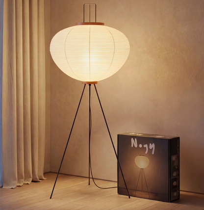 Noguchi Akari tripod rice paper floor lamp casting a soft diffused glow in a minimalist interior setting.