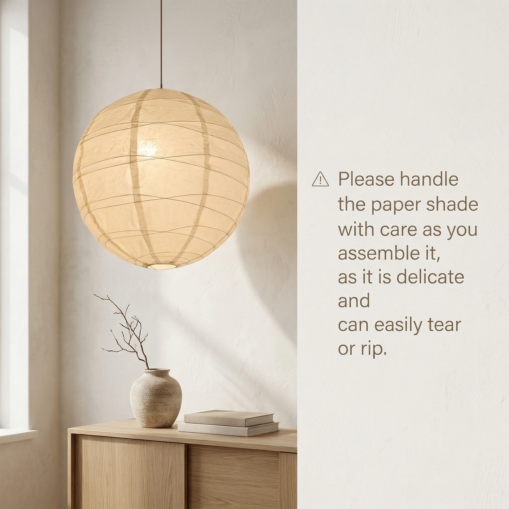 Delicate off-white rice paper globe pendant lantern on a wooden console with a warning to handle the paper shade with care